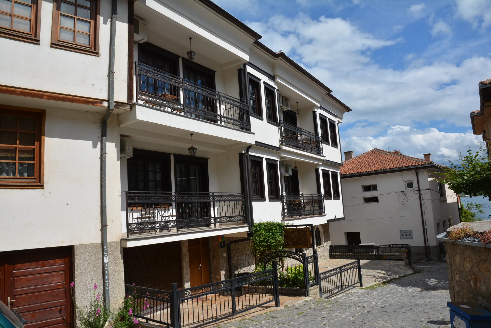 The white façade and dark timber balconies of Villa Dudanov